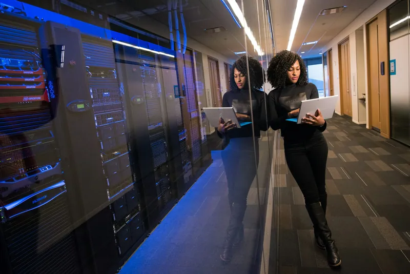 Two cloud engineers with laptops in a data centre corridor