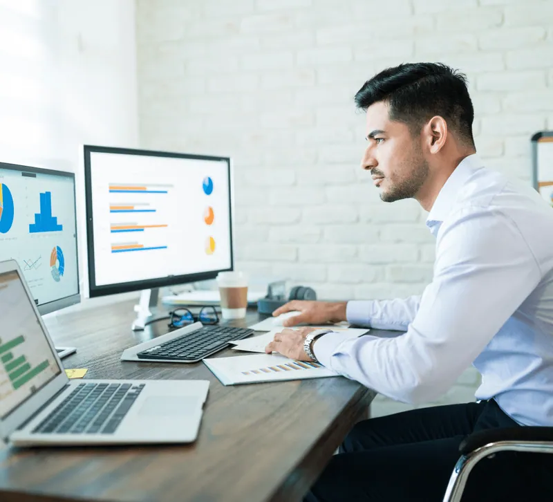 A finance analyst reviewing dashboards at his desk