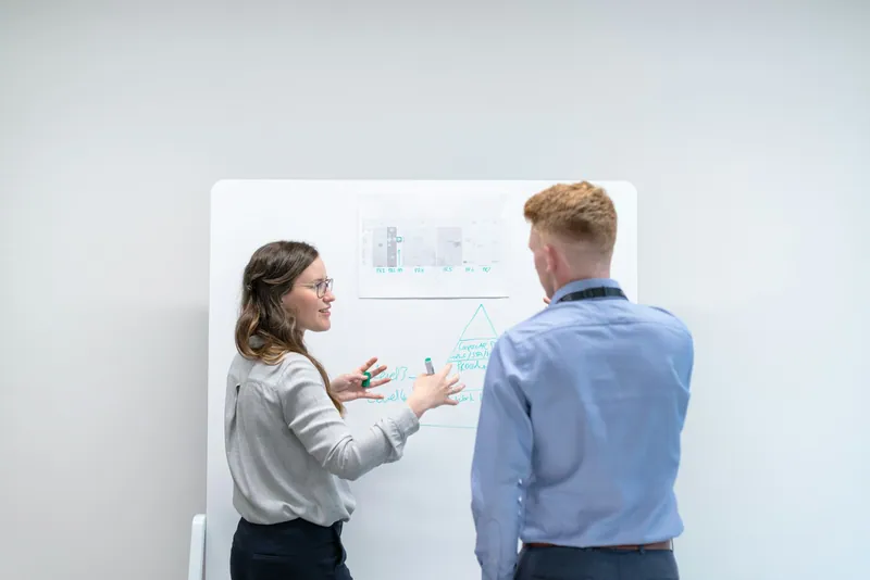 Two engineers discussing a system design at a whiteboard