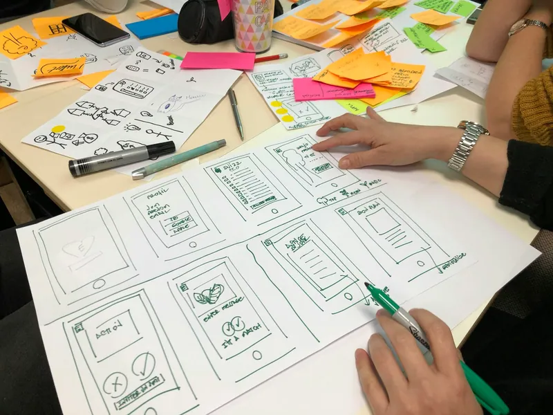 Hand-drawn interface wireframes and sticky notes on a desk